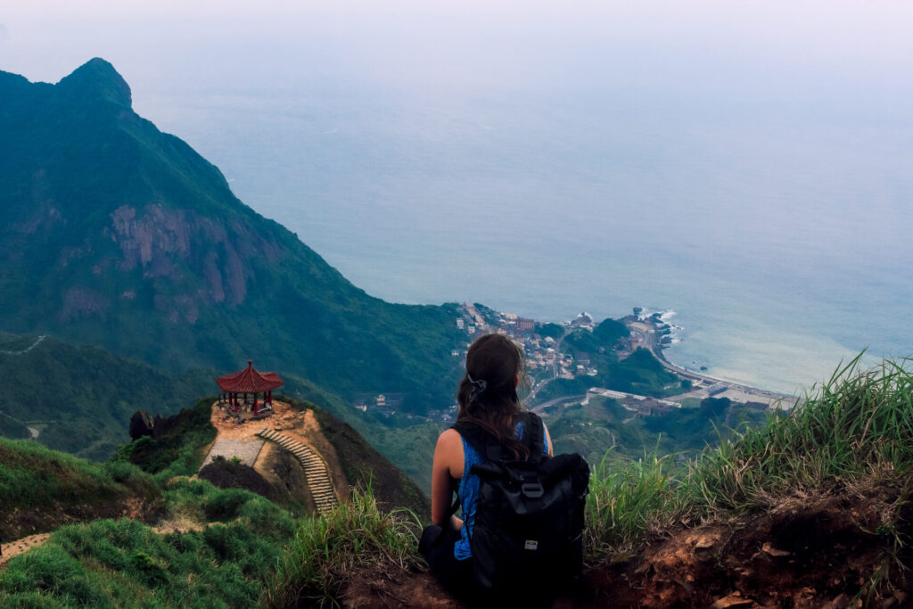Wini sitting on the cliff face overlooking the ocean on the Teapot Mountain Hike in Northeast Taiwan