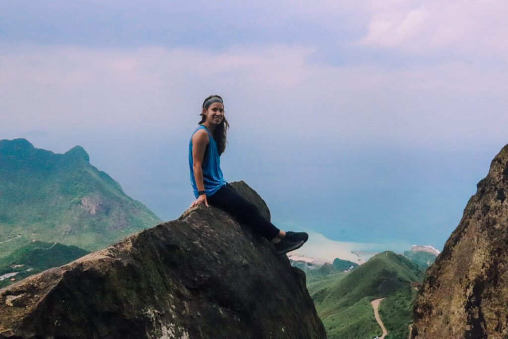 Wini sitting on the rock face overlooking the ocean on the Teapot Mountain Hike in Northeast Taiwan
