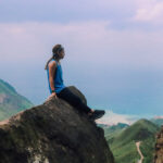 Wini sitting on the rock face overlooking the ocean on the Teapot Mountain Hike in Northeast Taiwan