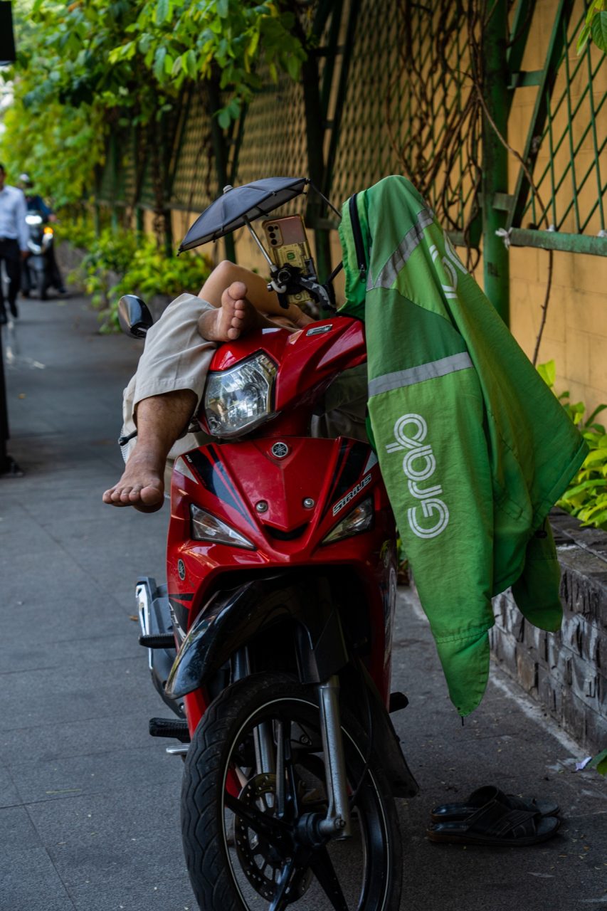 Grab driver sleeping on a scooter in Ho Chi Minh City, Vietnam