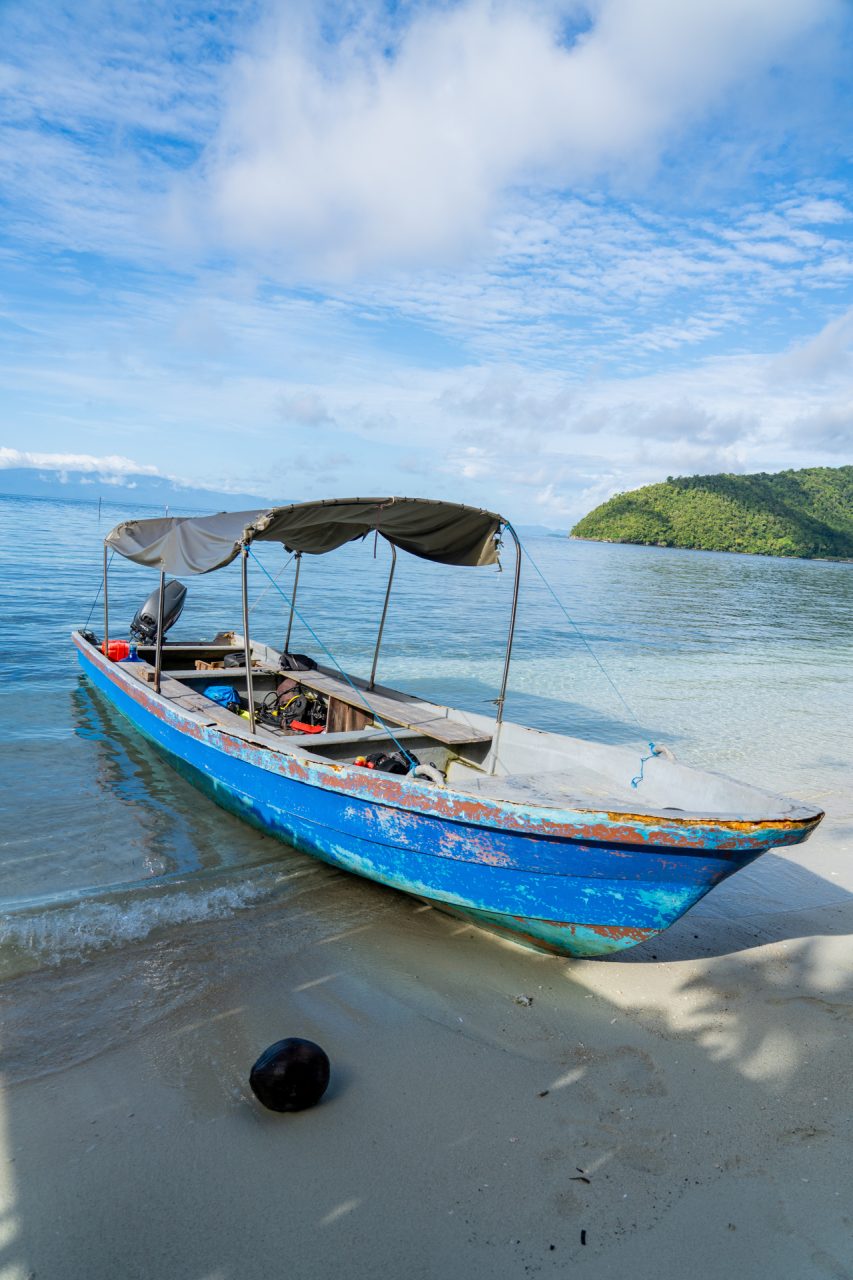 Small blue long boat in the ocean in Raja Ampat, Indonesia.