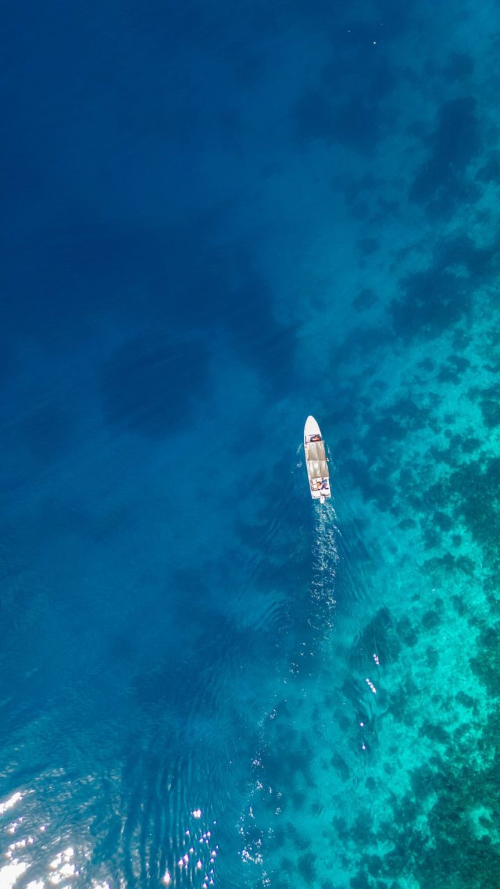 Long boat aerial view with clear coral reef below, Raja Ampat, Indonesia