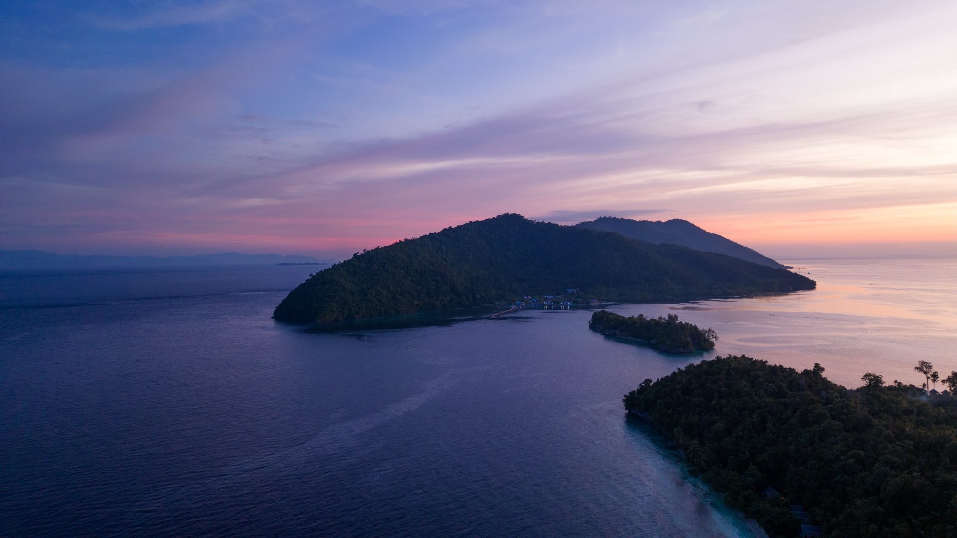 Drone shot of a sunset over several islands in Raja Ampat, Indonesia.