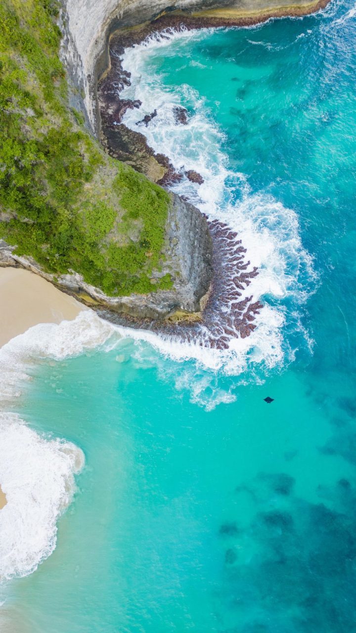 Kelingking Beach, Nusa Penida Giant Manta Ray and turquoise waters hitting the cliffs. Aerial drone view.