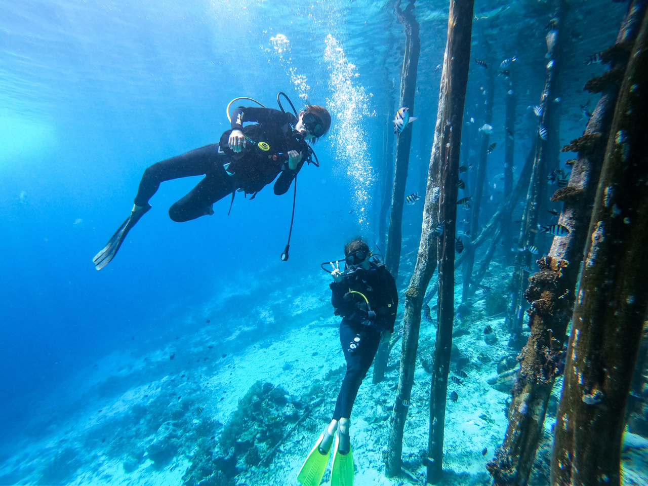 Two girls scuba diving Yenbuba Jetty, Raja Ampat, Indonesia