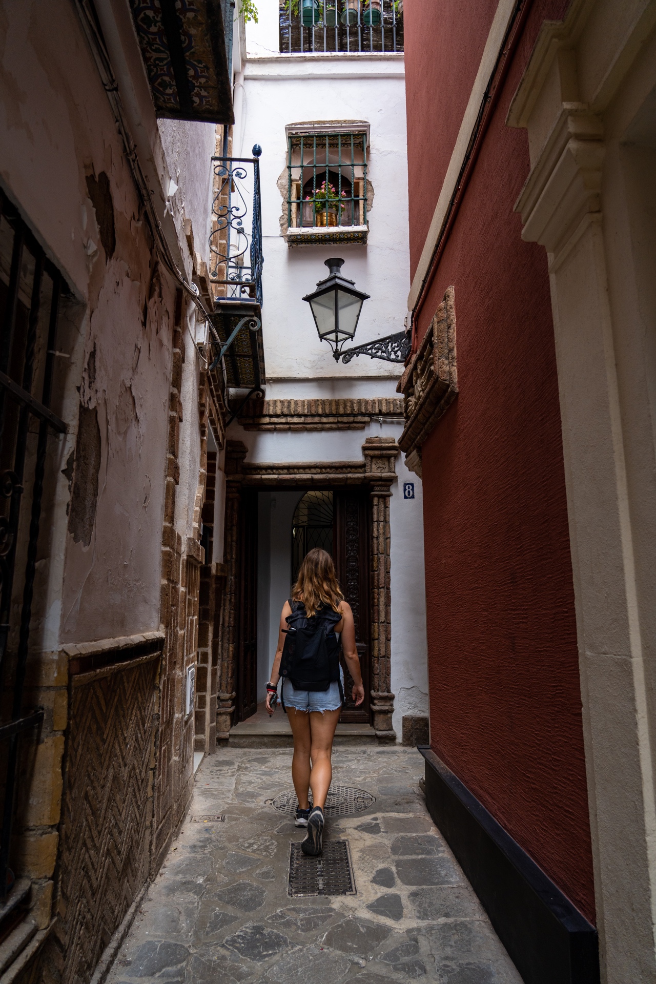 Woman walking through narrow, cobblestone street in Seville, Spain