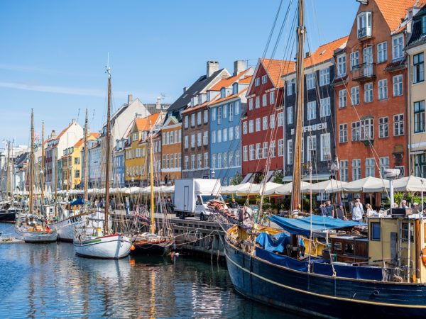 Nyhavn, Copenhagen, Denmark canal lined with boats on a blue sky summer day