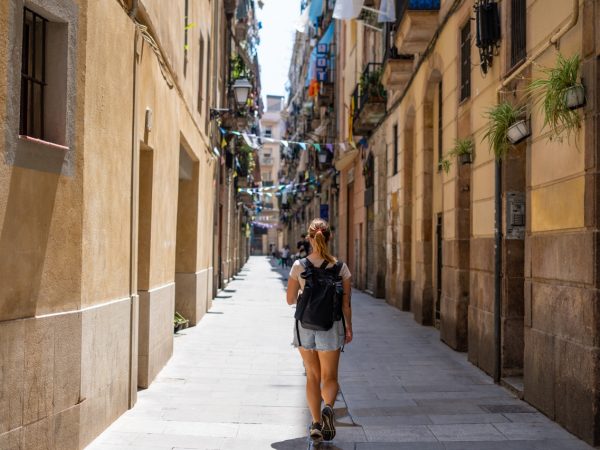 Backpacker girl walking through the quaint streets of Barcelona, Spain.