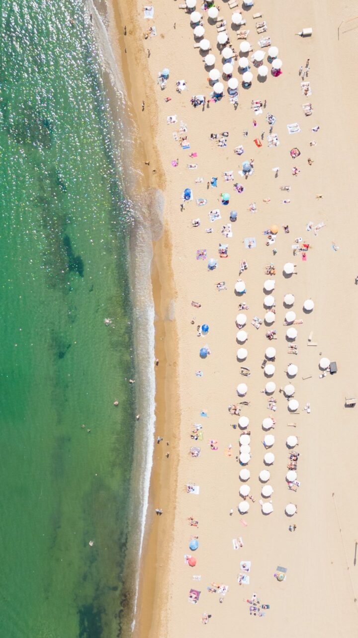 Spanish beach patchwork of towels and umbrellas from drone shot above in Barcelona, Spain.
